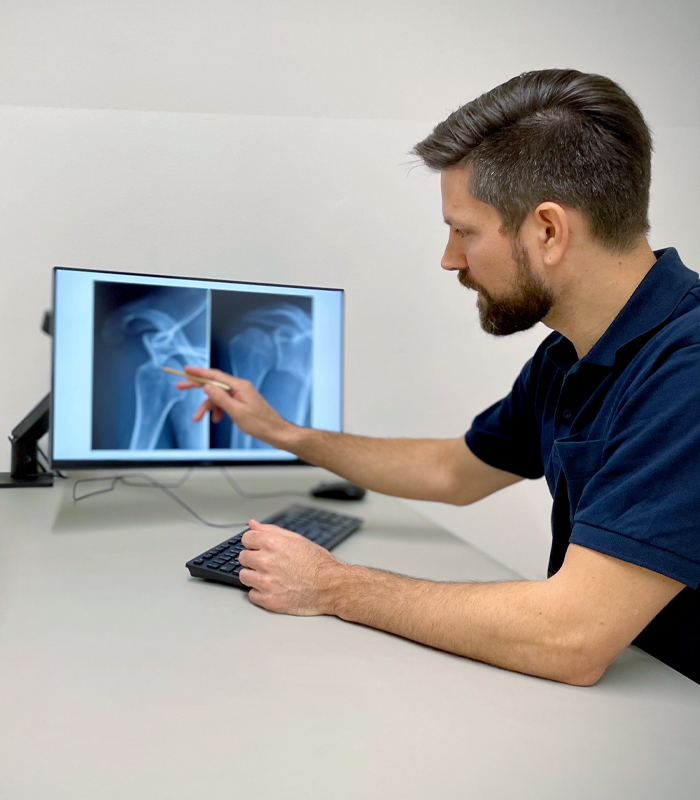 Dr Lukas Greiner erklärt am Monitor ein Röntgenbild